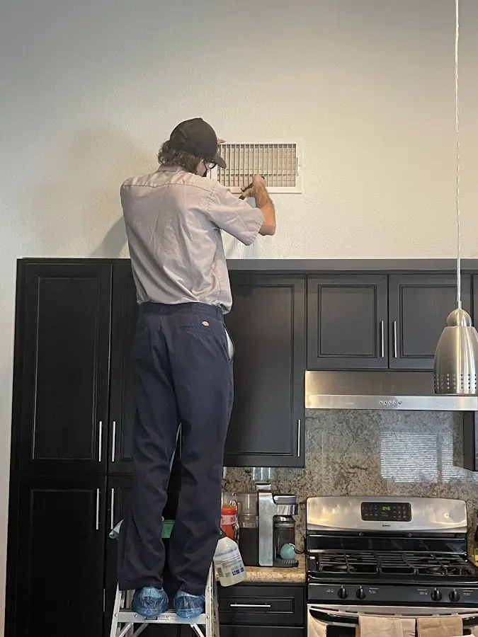 Technician inspecting an air vent during HVAC service in Rochester